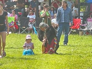 Elder knelt down with youth at a Powwow