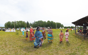 Screencap from the Pays Plat pow wow experience of women and girls walking at the pow wow.